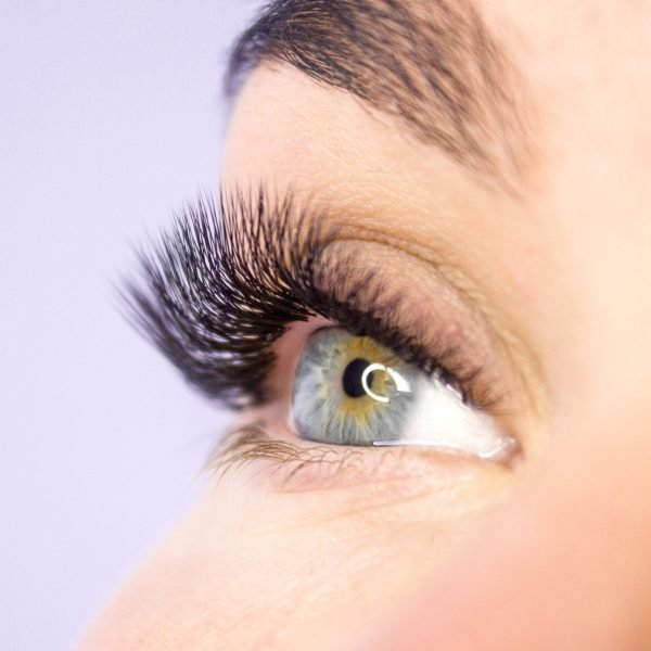 Beauty and fashion concept - Eyelash Extension Procedure. Woman Eye with Long false Eyelashes. Close up macro shot